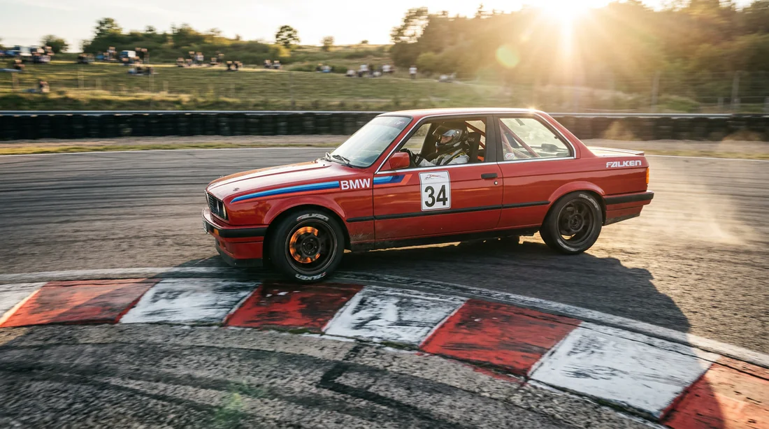BMW E30 négociant un virage au point d'attache sur un circuit de course.